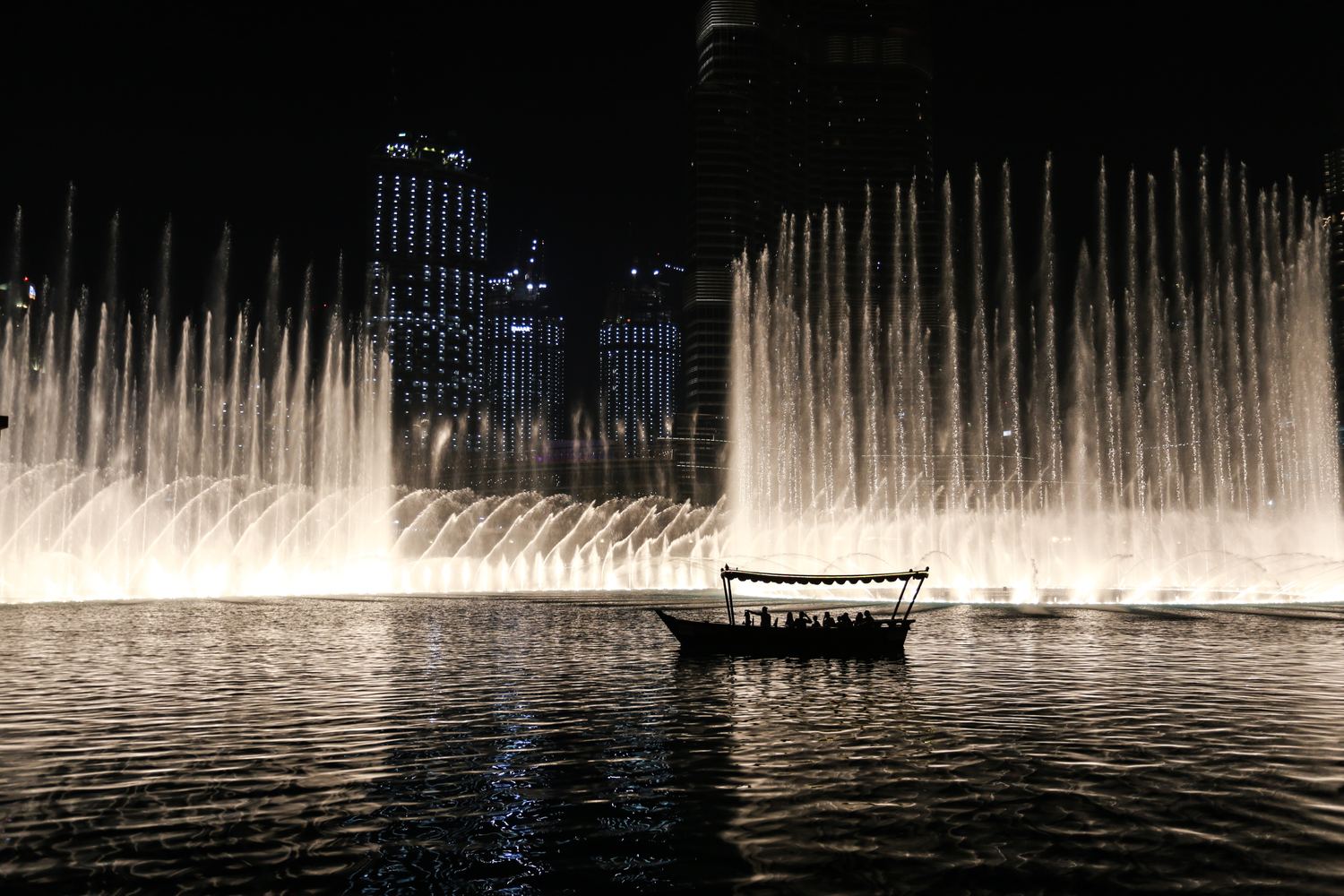 A wooden boat on the Burj Khalifa lake at night